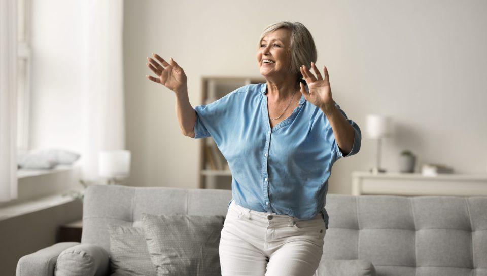 Older adult woman performs the Timed Up and Go (TUG) Test to assess mobility, balance, and fall risk, demonstrating a functional movement assessment used by physical therapists.